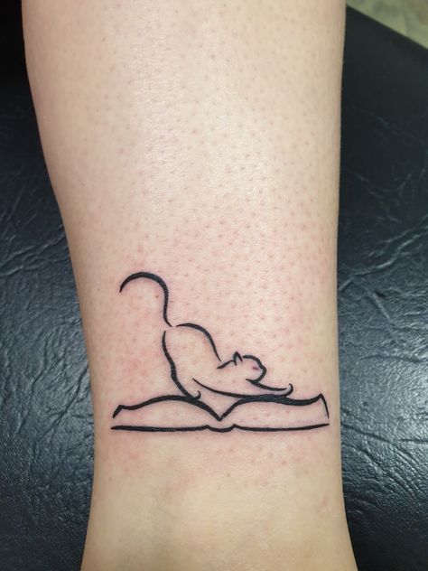 Cat and book tattoo Cat On A Book Tattoo, Book Tattoo With Cat, Cat Book Tattoo Ideas, Cat Sleeping On Books Tattoo, Tiny Book Tattoo Simple, Cat Books Tattoo, Minimal Book Tattoo Ideas, Cat Reading Book Tattoo, Cat Reading Tattoo