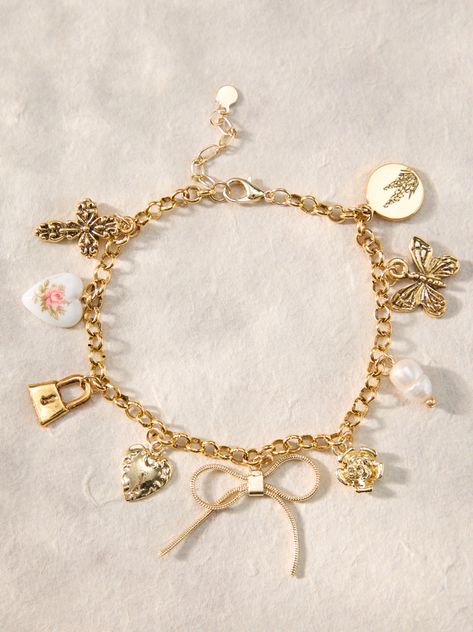 This bracelet features a bow charm with butterfly, cross, pearl, heart, lock, flower, and lilac accents, adding a touch of elegance to any outfit. Jewelry Gold Dainty, Altered State Jewelry, Jewelry Charm Bracelets, Gold Charm Jewelry, Coquette Charm Bracelet, Homemade Charm Bracelets, Pretty Jewellery Bracelets, Cute Jewelry Gold, Basic Jewelry Essentials