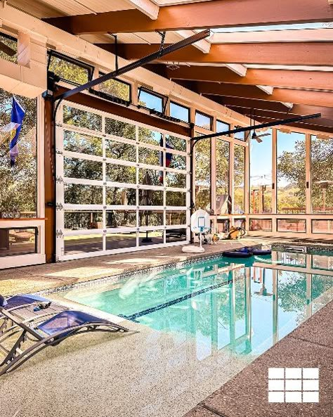 large glass garage door on pool house Pool In Garage, Indoor Pool Ideas Affordable, Sunroom Overlooking Pool, Inside Pool House Ideas, Glass Pool House, Pool House With Glass Garage Doors, Barndominium Indoor Pool, Indoor Pool And Greenhouse, Indoor Pool With Garage Doors