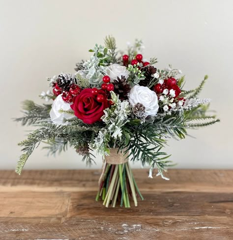 "DETAILS & SIZE  ---------------------------------------------------------- ❤ This classic  winter snow covered wedding bouquet is put together with high quality red and white silk flowers, red berries, babies breath, pinecones, eucalyptus and all sorts of different evergreens. The handle is also wrapped with twine and finished with a twine bow to give it a beautiful rustic touch. This bouquet is perfect for a wedding in winter or around Christmas. Available in 5 different sizes. The 12\" brides bouquet is photographed in the listings Before you choose the size of bouquet that you like, I would highly recommend that you measure the size against yourself to make sure that you choose the perfect size for you.  MATCHING BOUQUET: https://www.etsy.com/ca/listing/1572923381/red-wedding-bouquet-r Christmas Inspired Wedding, Holly Wedding Bouquet, Winter Wedding Red And White, Red White Green Wedding Flowers, Christmas Bridal Bouquet Winter Bride, Bridesmaid Bouquet Christmas, Outdoor Christmas Wedding Ideas, Rustic Christmas Wedding Bouquet, Wedding Flowers Christmas