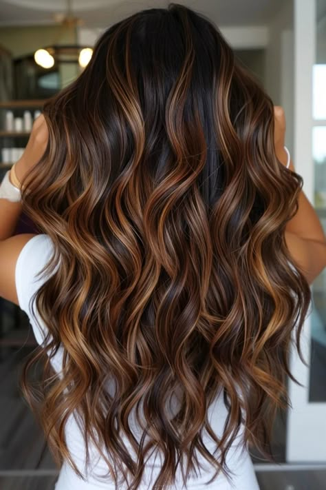 Woman with long, wavy brown hair with caramel highlights standing indoors. High Light Ideas For Brunettes, Caramel And Cinnamon Highlights, Dark Hair With Honey Balayage, Dark Brown Hair Highlights Caramel, Ashy Chocolate Brown Hair Balayage, Asian Caramel Highlights, Balayage Hair Copper Caramel, Dark Brown With Honey Highlights, Warm Brunette With Highlights