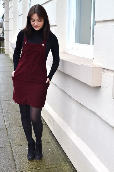 ktcrossthwaite: FASHION: THE LITTLE BURGUNDY DRESS Jumper Dress With Tights, Corduroy Jumper Dress Outfit, Corduroy Pinafore Dress Outfit, Overalls Dress Outfit Fall, How To Style Stockings With Dress, Dress With T Shirt Under, Burgundy Overalls Outfit, Overall Dress With Tights, Dark Red Dress Outfit