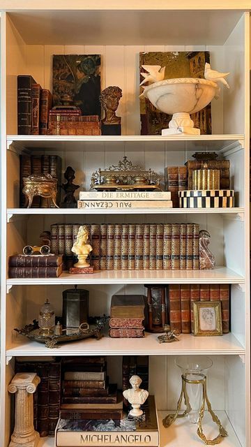 Antique & Vintage Home by Veronica Ashley on Instagram: "Style my vintage shelves with me ✨ It was time to transform my shelves back to a former version of themselves— with some updates, of course! Layering my own curated collection of vintage and antique treasures on these shelves gives me so much joy and I wanted to share that process with you. Stay tuned as I am back this week (and next) with lives sales lined up! So many more vintage and antique treasures to come. Follow along for more vintage and antique hauls, shop collections, live sales and more! ✨ Xx Veronica . . . . . #vintagedecor #shelfstyling #antiquelove #vintagehomedecor #onlinevintageshop #vintagehaul #shopvintage #curatedvintage #smallbusiness #vintageshop #antiquesofinstagram #estatesalefinds #thriftedandstyled #myc Bookshelf Ideas Vintage, Antique Shelf Decor Display, Wall Bookcase Decor, Decorating Shelves With Antiques, Victorian Shelf Decor, Vintage Bookcase Styling, How To Style Office Shelves, Antique Shelves Display Ideas, Parisian Shelves