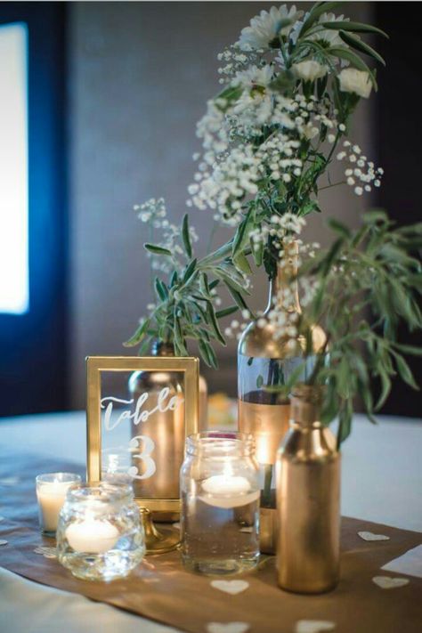 Gold centerpieces Easy Gold Centerpieces, Good Centerpieces, Black Gold And Green Centerpiece, Wine Bottle Wedding Decor Centerpieces, Simple Banquet Centerpieces, Green Gold And White Centerpieces, Elegant Gala Centerpieces, Greenery Ring Centerpiece, Wine Bottle Party Decorations