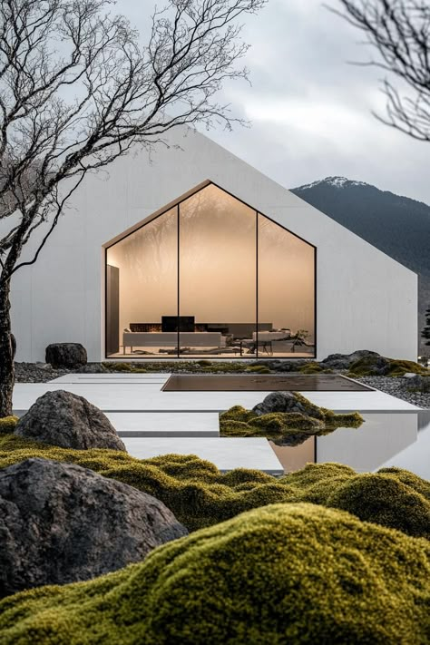 Modern minimalist symmetrical white concrete house facade with glass walls front yard with mossy rocks Japanese mountains in the background. Check out how these stunning modern houses create peaceful and strikingly Zen havens with their tranquil exterior designs. Nordic House Design Exterior, Concrete Glass House, Japanese Modern House Exterior, Japanese Style Architecture, Japanese Modern Architecture, Japanese Zen House, Concrete Minimalist House, Minimalist Modern House, Garden House Design