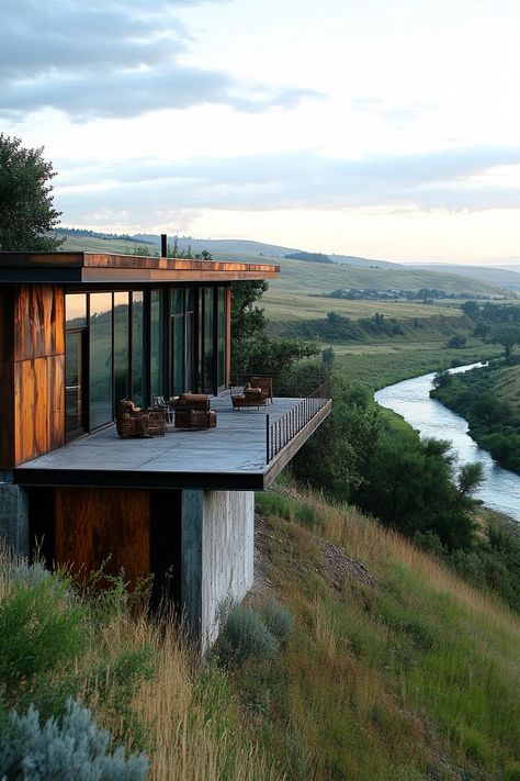 Earth sheltered modern house facade built into hillside with reclaimed wood and metal accents overlooking a river down the hill. Check out all of these stunning houses built into the hillside that look like they belong in a fairy tale. Homes On Sloped Lots, House Next To River, Hillside Architecture Concept, Metal Modern House, House Built Into Hillside Woods, Hills House Design, House On Steep Hill, Small House Built Into Hillside, Downhill House Design