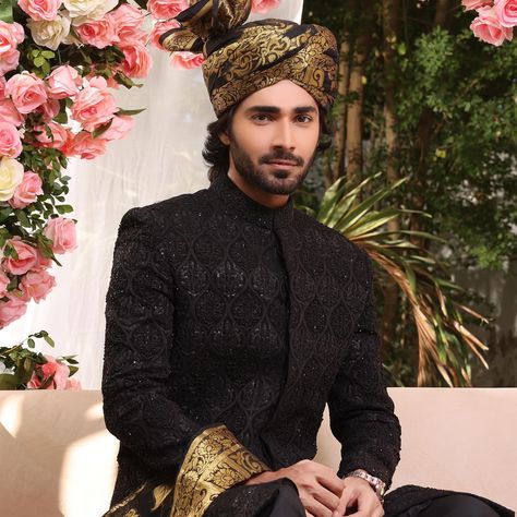 A timeless black sherwani ensemble named "ADEL" from TABEER-E-KHAWAB. The sherwani, in self-embroidered fabric, is paired with a silk pyjama. Complemented by a black turban with golden weaving and a coordinating stole, creating a monochrome masterpiece. The five-piece set includes a sherwani, kurta, pant set, turban, and stole, all crafted from high-quality materials like silk. This groomswear exudes sophistication and elegance, perfect for wedding occasions. The intricate embroidery and black- Black Sherwani, Black Turban, Silk Turban, Sherwani Groom, Indian Bridal Dress, Indian Bridal Fashion, Anarkali Suits, Embroidered Fabric, Dress Inspiration