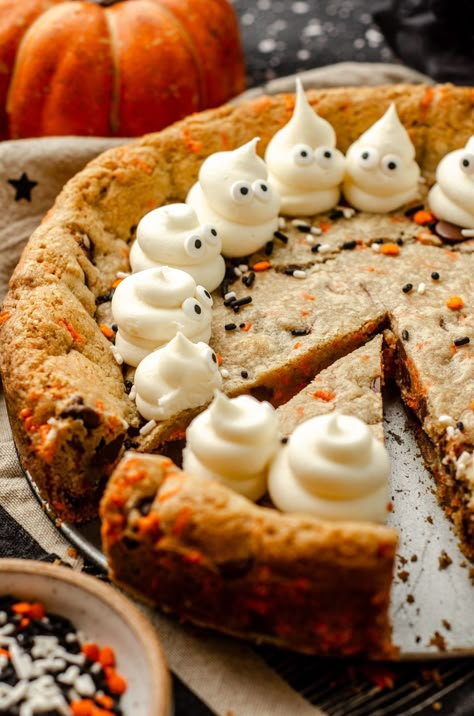 Turn any cookie cake into a Halloween spectacle with simple frosting ghosts. This easy Halloween cake recipe features chocolate chips and festive sprinkles for a fun Halloween cookie cake for kids and adults alike. This is a great option for Halloween potluck ideas for work or a Halloween party dessert recipe. Everyone will want more of this Halloween chocolate chip cookie cake. | halloween cookie cake designs easy | halloween cookie cake recipe | how to make frosting ghosts Halloween Slice And Bake Cookies, Halloween Food Adults, Ghost Cookie Cake, Spooky Cheesecake, Halloween Baking Ideas Easy, Halloween Deserts Ideas, Halloween Themed Dessert, Pumpkin Cookie Cake, Halloween Potluck Ideas For Work