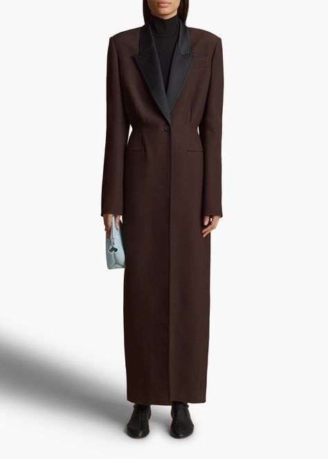 A tailored, single-breasted silhouette distinguished by an elongated profile. With satin lapels, nipped waist, chest pockets, and welt pockets. Dark Brown Coat, Build Wardrobe, Amsterdam Winter, Trend Coat, Minimalist Wardrobe Capsule, Brown Trench Coat, Wardrobe Capsule, Coat Trends, Leather Outerwear