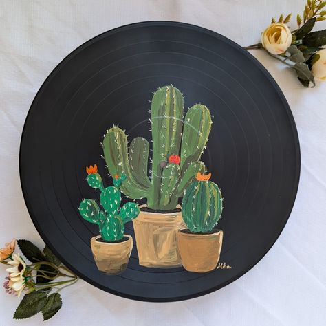 Hand-painted on a 12-inch vinyl record, this unique artwork features three charming cactuses in pots 🌵🎨 The playful design brings a touch of desert vibes and whimsy to any space, making it perfect for plant lovers and fans of quirky decor. This one-of-a-kind piece is ready to hang and adds a fun, creative accent to any home or office. A great gift for succulent enthusiasts or anyone who enjoys handmade, upcycled art! 🌟✨ Vinyl Record Painting Ideas, Record Art Ideas, Record Painting Ideas, Vinyl Records Art, Vinyl Record Painting, Vinyl Record Art Ideas, Record Painting, Vinyl Record Art, Quirky Decor