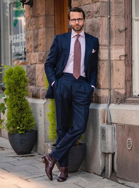 The outfit features a classic navy suit with a pink shirt, burgundy foulard tie with subtle detailing, and burgundy dress boots. Pink Dress Shirt Outfit, Navy Suit Pink Shirt, Classy Pink Dress, Suit Color Combinations, Dress Shirt Outfit, Interview Suits, Dress Leather Boots, Navy Suits, Blue Suit Men