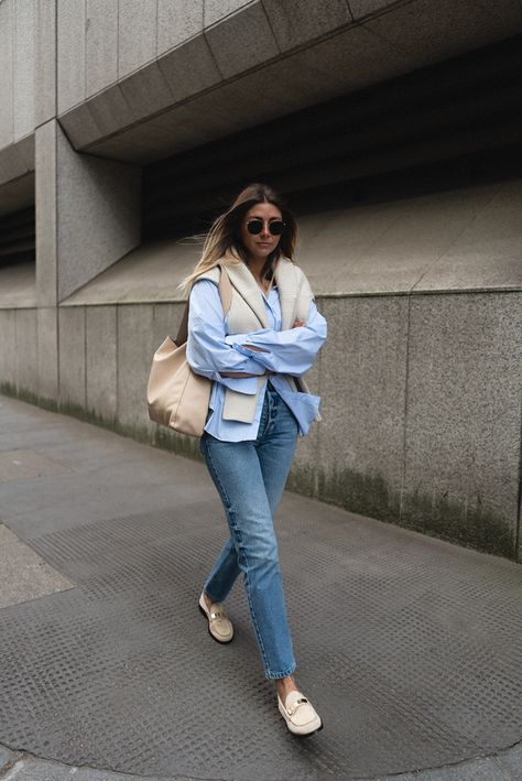 Emma Hill wears blue striped shirt, beige ribbed jumper over shoulders, mid wash straight leg jeans, beige suede loafers. Spring outfit Vionic Loafers Outfit, Beige Loafers Outfit Women, Beige Loafers Outfit, London Wardrobe, Loafers Outfit Women, Blue Striped Shirt Outfit, Spring Uniform, Loafer Outfits, Outfits With Striped Shirts