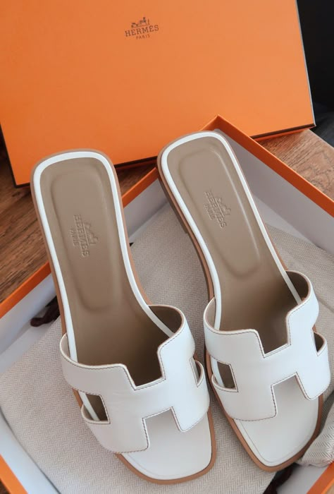 A classic pair of white Hermes sandals which are open toe and reveal some skin further elongating the legs. Tas Louis Vuitton, Hermes Slippers, Hermes Oran Sandals, Orange Box, Dr Shoes, Shoe Wishlist, Sandals Outfit, Hermes Shoes, Girly Shoes