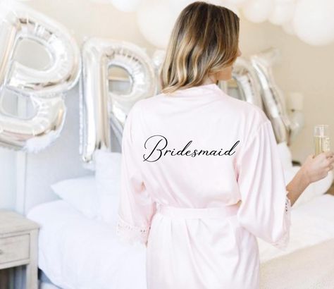 Make Your Wedding Morning Unforgettable with Our Personalized Bridesmaid Robes!  Our elegant satin robes with lace trim are the perfect addition to your special day. Whether you're preparing for the ceremony or capturing memories with your bridal party, these robes offer a picture-perfect look and make thoughtful, lasting gifts your bridesmaids will cherish.   ✨ Why Choose Our Robes? - Personalized Touch: Add a name, role, or custom text to make each robe unique.   - Multiple Uses: Perfect for wedding mornings, bridal showers, bachelorette parties, and keepsakes.   - Timeless Elegance: Smooth satin with delicate lace detailing ensures a luxurious feel.   ✨ Product Details: - Design: Classic short robe with a banded collar, self-tie waist, and lace trim along the sleeves and hem.   Sizing: