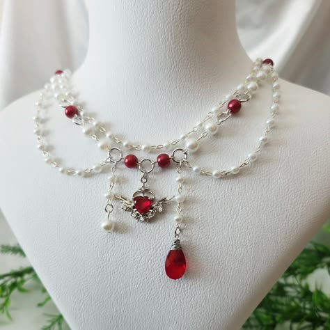 Red and White Beaded Angelcore Necklace with Silver Plated Heart Wing Charm Available in my Etsy shop ExangelsJewelry.etsy.com . . #angelcoreaesthetic #angelcorenecklace #whitebeadedjewelry #grungenecklace #fairycorejewelry #fairycorenecklace #handmadejewelry #beadednecklace #chunkynecklace #princesscorejewelry #princesscoreaesthetic #aestheticgrunge Fairycore Necklace, Grunge Necklace, Red Beaded Necklace, Necklace Y2k, Pretty Jewelry Necklaces, Diy Jewelry Unique, Tooth Necklace, Polymer Clay Jewelry Diy, Beaded Jewels