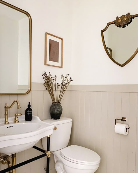 We are loving the warmth in this bathroom! This wainscoting allows the two different colors used in this space and we are loving it! These brass accents like the faucet and the trim around the mirror bring in the vintage charm and the other mirror on the side wall helps open up this space even more! | Signature Hardware #bathroom #vintage #vintagebathroom #wainscoating #brassaccents #warmtones Cottage Bathroom, Casa Vintage, Casa Container, Downstairs Bathroom, Upstairs Bathrooms, Bathroom Renos, House Bathroom, My New Room, Bathroom Makeover