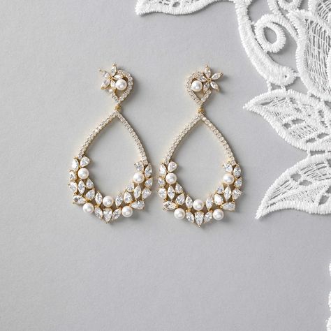 These earrings feature a teardrop-shaped hoop adorned with a charming cluster of pearls, pear, and marquise cut CZ jewels on the lower half. Boasting a length of 2.25 inches, these earrings have titanium post backs and are crafted from rhodium or gold plated brass with AAA CZ stones. Plus, they are lead, nickel, and cadmium free for a worry-free and luxurious accessory. Teardrop Bridal Earrings, 2025 Wedding, Black And White Earrings, Weaving Ideas, Bridal Accessories Jewelry, Gold Bridal Earrings, Bride Accessories, Jewellery Ideas, Hot Nails