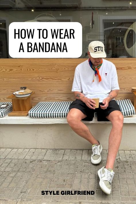 image of a man sitting on a bench wearing a white baseball cap, white t-shirt, orange patterned bandana around his neck, dark shorts, and Nike sneakers. Text on-screen reads: how to wear a bandana How To Tie A Neckerchief Men, Men Summer Scarf, Bandana Around Neck Outfit Men, Bandana Scarf Outfit Men, Bandana Neck Scarf Outfit Men, Neck Bandana Outfit Men, Neckerchief Outfit Men, Mens Bandana Style, Bandana Styles For Men