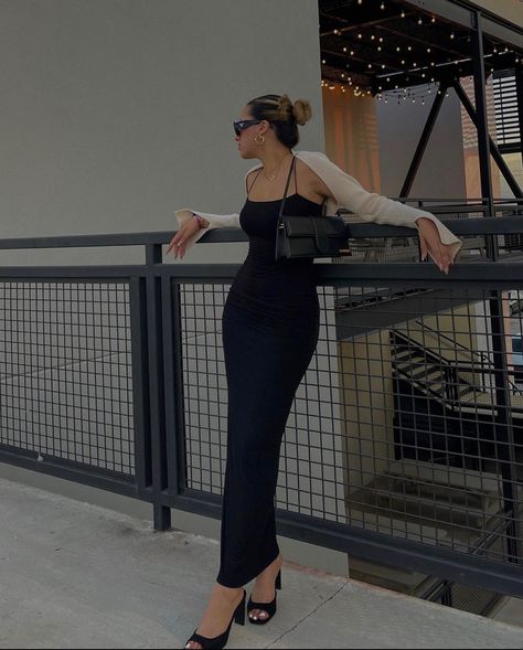 A girl is leaning against a railing with a long black, skin tight dress on. She’s  wearing black heels, a beige shrug, and a little black purse. Body Con Maxi Dress Outfit, Brunch Date Outfit Summer, Black Bodycon Dress Outfit, Long Black Dress Outfit, Long Black Bodycon Dress, Tight Maxi Dress, Black Maxi Dress Outfit, Bodycon Dress Outfit, Black Midi Dress Bodycon