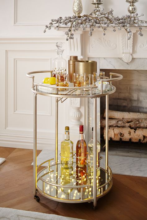 Pop open a bottle of bubbly and toast the new year with plenty of shimmer and shine. We've raised the bar for at-home entertaining with our Round 2-Tier Bar Cart. Crafted of wrought iron with a champagne finish, our stylish cart boasts a top shelf of tempered glass and a lower shelf with a mirrored surface and three bottle rings to store your favorite libations. A rack attached to the top shelf conveniently stores stemware. Exclusively Pier 1 Imports. Round Bar Cart, Holiday Bar Cart, Bandeja Bar, Andee Layne, Diy Bar Cart, Holiday Bar, Gold Bar Cart, Outside Bars, Bar Cart Styling