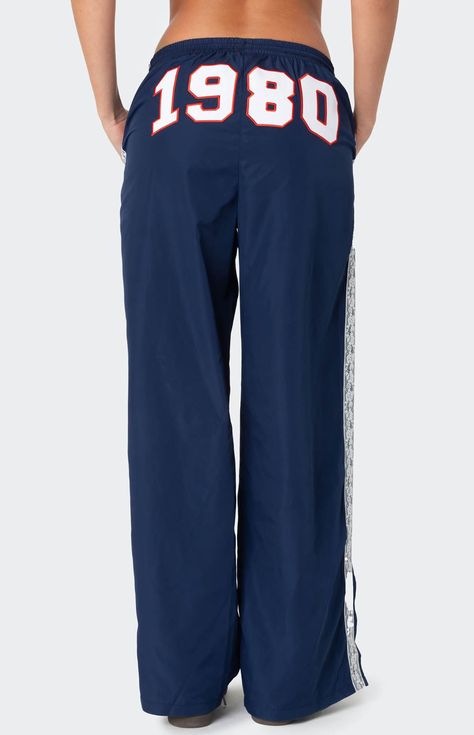 These Edikted 1980 Nylon Track Pants offer both style and comfort, making them perfect for a sporty yet fashionable look. They're ideal for any activity, ensuring you feel comfortable and confident throughout your entire day. Track pantsLace stripe detailingSlitted hemAdjustable waist tieEmbroidered graphic textPolyesterModel wears size SModel height is 5'8Item care: Machine wash at maximum 30C, wash with similar colors, do not bleach, do not tumble dry, iron at a maximum of 110C, do not dry clean. Edikted Womens 1980 Nylon Track Pants - Blue size Medium Sweatpants With Words On Back, White Track Pants, Nylon Track Pants, Graphic Sweatpants, Hip Hop Pants, Birthday Fits, Elastic Pants, Gym Fits, Future Outfit