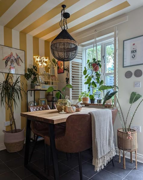 Dining room with yellow and white striped walls, brown leather bench seats, wooden table, and lots of plants Painted Dining Room, Painted Stripes, Apartment Dining Room, Gold Dining, Bench Seats, Striped Walls, Rental Apartment, Parisian Cafe, Dining Room Makeover