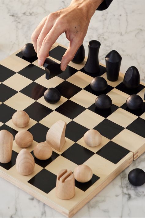 Foldable wooden chess set designed by Panisa Khunprasert. This chess set features minimalist turned-wood chess pieces that evoke modern sculptures. Subtle details are employed to identify the various pieces: a diagonal slice on the oval-shaped Bishop suggests a liturgical headpiece; two deep grooves create castle turrets for the cylindrical Rook; the Knight’s arched lines follow the shape of a horse’s head. Flat Chess Pieces, How To Make Chess Pieces, Clay Chess, Chess Board Design, Modern Chess Set, Chess Design, Tile Making, Moma Store, Knight Chess