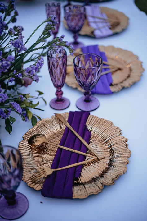 I placed three shades of purple and complimented with Purple shaded Glassware and blended up with Gold. Purple And Gold Event Decor, Purple And Rose Gold Party, Royal Blue Purple And Gold Wedding, Purple And Gold Wedding Theme Decor, Purple Gold Birthday Party Decoration, Purple And Gold Party Decorations Ideas, Gold Chargers Place Setting, Gold And Purple Aesthetic, Purple And Gold Party Decorations