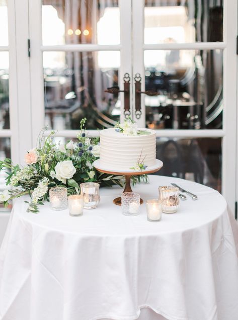 White one tier cake with ivory linen, green, peach, and ivory floral arrangements and mixed glass and metal votives. Intimate Wedding at La Valencia Hotel in La Jolla by Cavin Elizabeth Photography Wedding Cake Display Table, Wedding Cake Table Decorations, La Valencia Hotel, Intimate Winter Wedding, Cake Display Table, Wedding Cake Setting, Table Floral Arrangements, Wedding Cake Display, Single Tier Cake