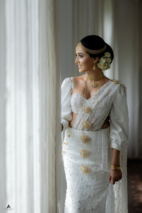 Discover the epitome of elegance with this off-white Kandyan bridal saree, adorned with intricate beadwork and paired with a modern blouse design featuring stylish cut-outs. Perfect for brides who desire a blend of tradition and contemporary fashion. Embrace the delicate balance of classic charm and modern sophistication for your special day with Lassana Saree's exclusive bridal collection.  #KandyanBridalSaree #BridalFashion #SriLankanBride #LassanaSaree Brides In White Saree, Modern Wedding Saree, Traditional Kandyan Bride, Bridal Saree Look For Wedding, Modern Kandyan Saree Designs, Kandyan Saree Designs, Modern Blouse Design, Kandyan Bridal Saree, Saree Look For Wedding