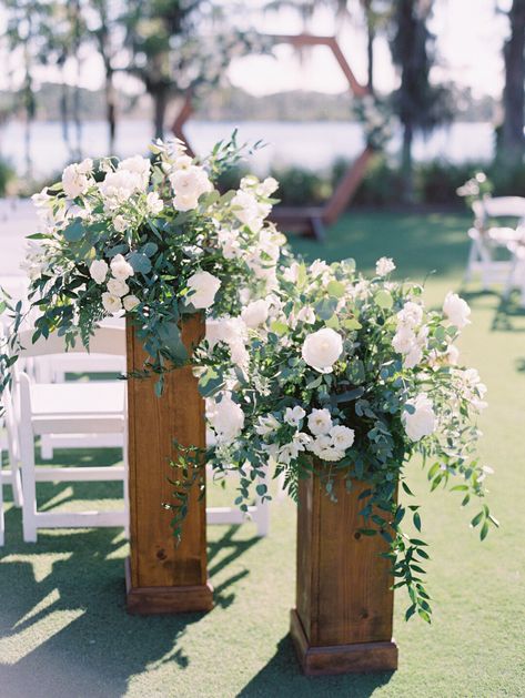 White and Green Floral Altar pieces in a garden style atop of natural wood stands. Floral Stand Wedding Ceremony, Wedding Pillars Ceremony Floral Arrangements, Wedding Aisle Columns, Wedding Ceremony Column Flowers, Wedding Flowers On Pedestal, Pedestal Flowers Wedding Ceremony, Nature Wedding Ceremony Decor, Ceremony Arrangements On Pedestals, Standing Floral Arrangements Wedding