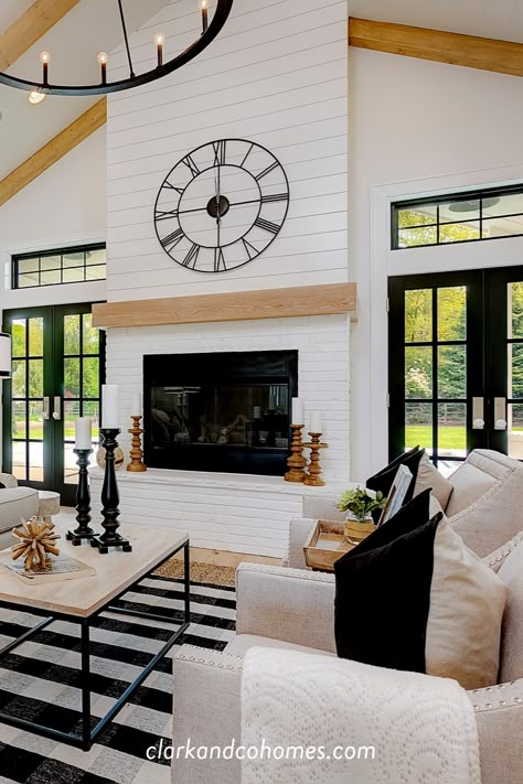 The great room in this Modern Farmhouse home features a custom painted brick and shiplap fireplace with a wood stained mantle that coordinates with the natural wood beams of the vaulted ceiling. #modernfarmhouse #vaultedceiling #beams #fireplace #shiplap #paintedbrick #blackandwhite Brick And Shiplap Fireplace, Doors To Deck, Brick And Shiplap, Great Room Addition, Luxury Mobile Homes, Vaulted Ceiling Living Room, Shiplap Fireplace, Fireplace Built Ins, Modern Farmhouse Home