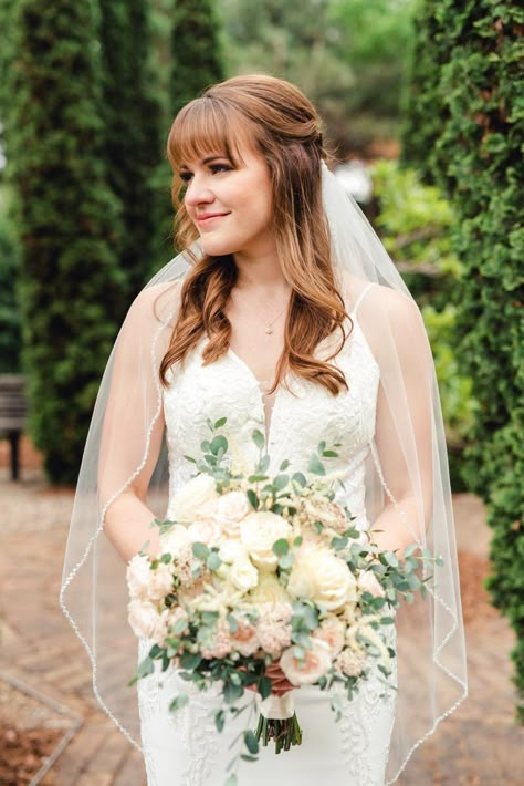 Bride with bangs with half up hairstyle holding bouquet of flowers Bridal Hair Down With Fringe, Fringe Wedding Hair, Bride Hairstyles Bangs, Bride Bangs, Wedding Hair Fringe Bangs, Bride With Bangs Hairstyles, Half Up Wedding Hair With Bangs, Bridal Hair With Side Bangs, Bride Hair Bangs