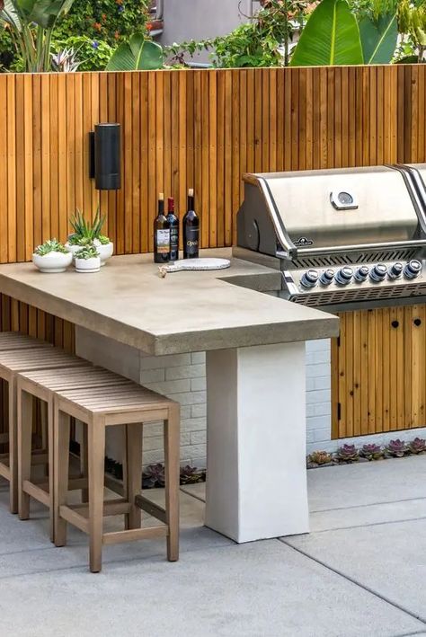 A modern outdoor bbq area with a large tiled unit with a grill, a concrete countertop, wooden stools and potted greenery Outdoor Kitchen Design Layout Grill Area, Outdoor Kitchen Design Modern, Outdoor Bbq Area, Outdoor Grill Station, Outdoor Barbeque, Kitchen Design Layout, Grill Station, Kitchen Design Diy, Outdoor Kitchen Plans