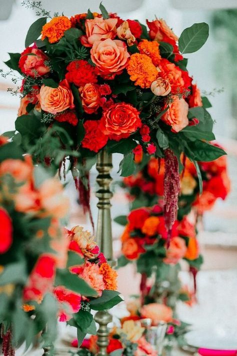 Red and tangerine for fall wedding colors 2025,red bridesmaid dresses, white bridal gown, grey groom suit, tangerine tie and tangerine flowers corsage, white and tangerine flowers and greenery of bouquets, ceremony arch, reception centerpieces and wedding cake décor, white wedding cake. Coral Red Wedding Theme, Indian Wedding Flower Arrangements, Indian Wedding Bouquet, Orange Indian Wedding, Flower Cocktails, Wedding Colors 2025, Grey Groom Suit, Indian Wedding Centerpieces, White Wedding Table Setting