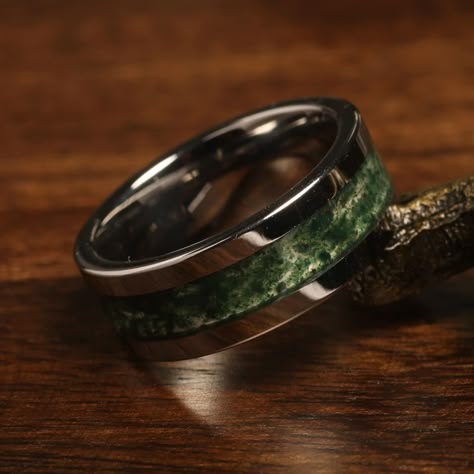 "Elevate your special moments with our stunning Green Moss Agate Tungsten Ring. This unique piece is not just a symbol of commitment but a statement of individuality and style. Crafted with high-quality black tungsten, this ring features a mesmerizing green moss agate inlay that showcases the beauty of nature. As a unisex ring, it offers versatility for both men and women seeking an extraordinary wedding band, anniversary token, or an engagement or promise ring. The black tungsten band provides Stone Rings Mens, Unique Male Rings Men Wedding Bands, Mens Wedding Ring Hunting, Men's Wedding Rings Vintage, Wedding Rings Men Vintage, Nut Mens Wedding Rings, Natural Weddings Rings, Luxury Agate Men's Ring For Formal Occasions, Luxury Men's Green Ring With Accent Stones