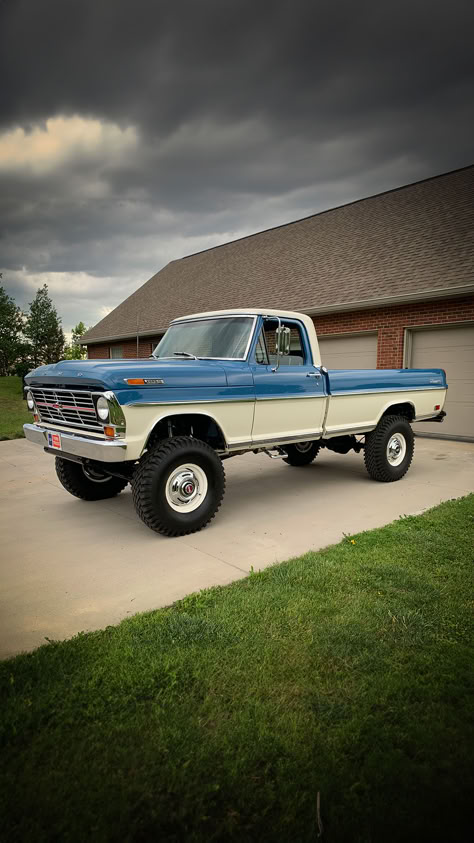 A beautifully maintained two-tone Ford Highboy pickup truck in blue and white, parked confidently on a concrete driveway. The towering stance of the truck is accentuated by large, robust tires and its classic design. Overcast skies loom above, suggesting an impending storm, yet the Highboy stands as a testament to the enduring strength and style of Ford's truck legacy. White Pickup Truck, Ford Highboy, Country Trucks, Future Trucks, Vintage Pickup, White Truck, Custom Pickup Trucks, Vintage Pickup Trucks, Old Ford Trucks