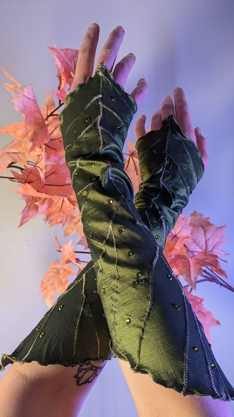 Wearable leaves! Don these deluxe leaf gauntlets to elevate your LARP, Ren Faire, or fantasy costume. Made out of a polyester/spandex stretch taffeta in Spring or Forest green, with extra embroidery details and glass rhinestones for some dewy sparkle. Approx. 15 inches long from tip to tip. Mystery drawstring storage bag included with every leafy order! Looking for a different color? Contact me for a custom listing! Long & Short Leaf Gauntlets are also available in the shop! Otgw Beast Costume, Warrior Elf Cosplay, Layered Ren Faire Outfit, Fallen Fairy Costume, Leaf Dress Art, Forest Themed Costume, Green Fairy Ren Faire, Clothes Made Of Leaves, Dragonfly Inspired Fashion