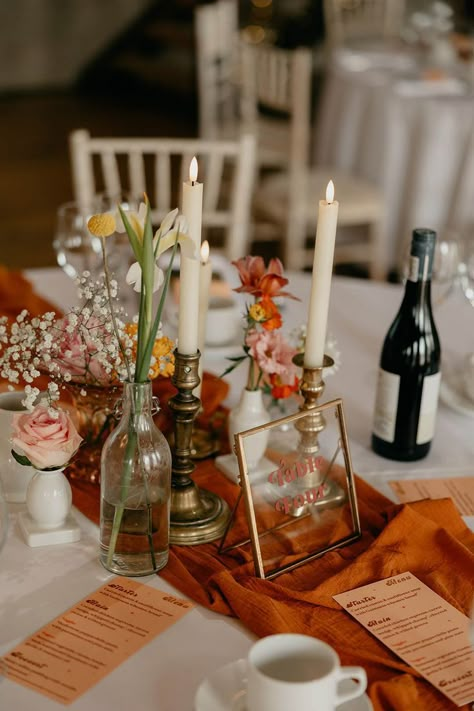 Round tables for wedding reception with orange table runners and orange wedding menus with white candles, glass vases of flowers and a clear gold photo frame table name Photo Frame Table, Wedding Table Set, Round Wedding Tables, Round Table Decor, Yellow Wedding Flowers, Yellow Theme, Ireland Wedding, Candle Holders Wedding, Wedding Table Flowers