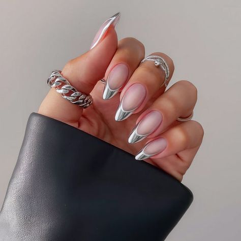 A striking almond-shaped manicure featuring a chrome silver metallic finish on the tips. The nails have a translucent pink base that adds a modern, futuristic touch. Perfect for those who love a sleek, edgy look. Silver Chrome French Tip Nails, Silver Almond Nails, Chrome French Tip, Chrome French, Modern Futuristic, Chrome Silver, Almond Shaped, Types Of Nails, Edgy Look