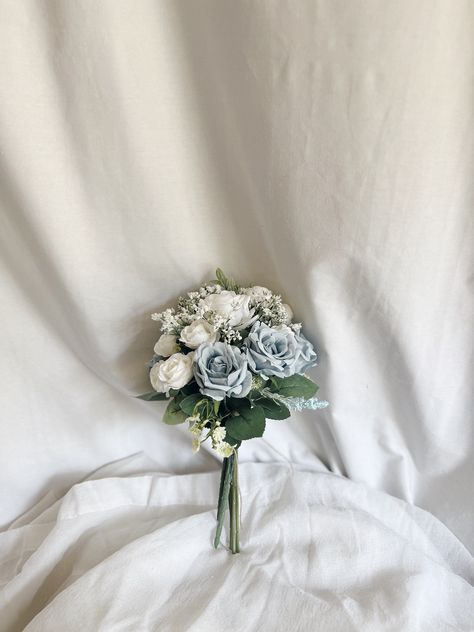 This beautiful bunch of faux flowers consists of roses and buds of white and dusty blue colors accompanied with faux fillers. It will be a perfect touch to any table.  Arrangement measures: W - 6" , H - 11 "approx. Matching bridal and bridesmaids bouquets, toss bouquet, corsages and boutonnières and other accessories are available. Blue Flowers Centerpiece, Blue And White Boutonniere, Simple Wedding Table Centerpieces, Blue Flower Centerpieces, Centerpieces Blue, Small Bridesmaid Bouquets, Kou Diabolik Lovers, Toss Bouquet, Decorating Wedding