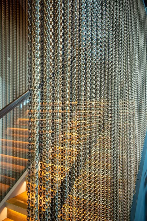 Working closely with WFC Contractors Ltd, we were asked to specify a suitable metal to go alongside the glass bannister by the staircase. To achieve the desired look, we supplied our Kriskadecor chains for either side of the staircase. These were finished in Coffee 20221, Brown 20206, Sand 20228, and Apricot 20220. Each chain from left to right was finished in a different colour, in vertical stripes to give the curtain a textured look. Metal Chain Curtain, Glass Bannister, Shed Living, Chain Curtain, Luxury Retail Store, Mail Room, Design Studio Office, String Curtains, Glass Curtain