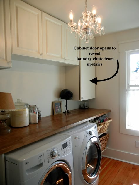 Beautiful laundry room with folding counter, hidden laundry chute, and crystal chandelier. Laundry Room Chute Ideas, Laundry Room With Chandelier, Hidden Laundry Chute, Laundry Shoot Ideas Bathroom, Hidden Laundry Shoot Ideas, Laundry Shoot Cabinet, Laundry Room Shoot Ideas, Hidden Laundry Shoot, Laundry Room With Laundry Chute