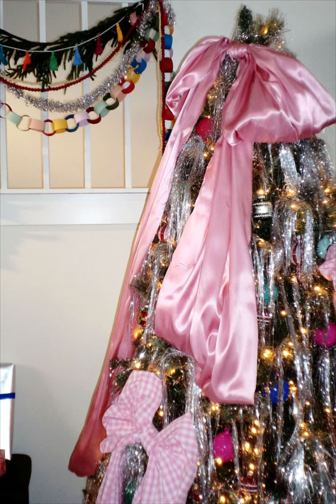 We're not saying we invented the oversized Christmas tree bow trend, but we definitely perfected it. DIY oversized satin bows and silver tinsel create the perfect whimsical retro Christmas tree. #retrochristmas #nostalgicholiday #bhg Retro Tinsel Christmas Tree, Maximalist Christmas Aesthetic, Tinsel Bow Christmas Tree, Maximalist Holiday Decor, Bow Christmas Aesthetic, Eloise Christmas Tree, Bows And Tinsel Christmas Tree, Oversized Bow Christmas Tree, Tinsel Christmas Decorations