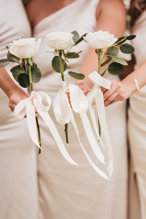 Bridesmaids in white ivory one shoulder bridesmaid dresses holding white rose single stem bouquets with white ribbon | wedding flower trends | simple and minimalist wedding flowers | Hannah Miles Photography Single Rose For Bridesmaids, Bridesmaids Not Holding Flowers, Single Stem Bridesmaid Bouquet White, Single Stem Flower Bridesmaid, Single White Rose Bridesmaid, Simple Wedding Bouquets Bridesmaid, One Rose Bridesmaid Bouquet, Simple Brides Bouquet, Bridesmaid Holding Single Flower