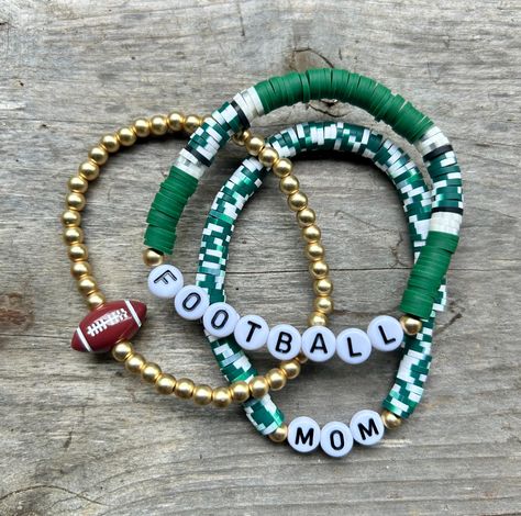 These are fun bracelets that are personalized perfectly for you! This stack is a set of {3} bracelets. The set includes two Heishi disc bracelets (the words can be changed) & a gold bracelet with a ball bead on it.  I change the bead color to match your school/team colors. I will also change the 'football' bead to whichever sport you choose. These stacks can be personalized, and bracelets added. You can reach out to me with any questions or personalization ideas! If you want bracelets added, rea Cheap Sports Wristband With Team Spirit, Cheap Personalized Stretch Bracelet For Sports, Cheap Sporty Bracelets For Gifts, Cheap Black Beaded Bracelets For Team Spirit, Cheap Team Spirit Stretch Bracelet As Gift, Heishi Soccer Bracelet, Cheap Beaded Stretch Bracelet For Sports Events, Cheap Team Spirit Sports Jewelry, Cheap School Spirit Bracelets As A Gift