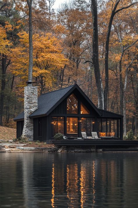 A modern cabin reflecting in a tranquil lake surrounded by autumn trees. Uncover how sleek design, cozy woodwork, and a dash of minimalist charm are transforming cabins from rustic hideaways to luxurious retreats. Lake House Cabin Exterior, Cabins By The Lake, Homes In Switzerland, Minimalist Lake House, Mountain Lake Cabin, House In Mountains Dream Homes, House Design Cabin, Corrupted Chaos, Mountain Cabin Exterior