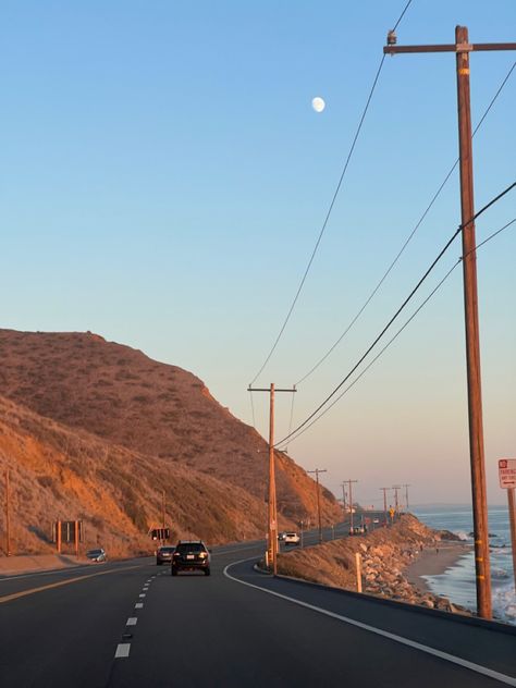 pacific coast highway on a curve around an amber mountain at sunset with moon visible in the still-blue sky just beyond the telephone wires, ocean tide coming in toward the rocky beach off to the right Pacific Highway California, California Cool Aesthetic, Highway One California, Norcal Beach Aesthetic, Rural California Aesthetic, Sonoma California Aesthetic, Y2k California Aesthetic, Southern California Aesthetic Home, Highways Aesthetic