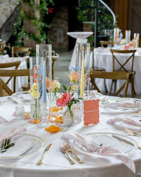 you kidding me 🥲 these pastel tapers added so much to this tablescape!! A sweet bud quartet paired with a trio of taper candles is one of our favorite ways to add a little something something to a guest table. here, we opted for mini centerpieces on some of our farm tables + invested in smilax vines to give life to the venue overall - which is something ALL your guests can enjoy, no matter which table they’re sat at. It’s all about creating an atmosphere! Planning @perfectlyplannedtx Venue... Simple Pastel Centerpieces, Outside Wedding Table Set Up, Pastel Wedding Round Table, Bud Vases And Taper Candles Centerpiece, Bud Vase Table Centerpiece, Simple Garden Wedding Decorations, Pastel Round Table Decor, Colorful Wedding Table Decorations, Simple Wedding Arrangements