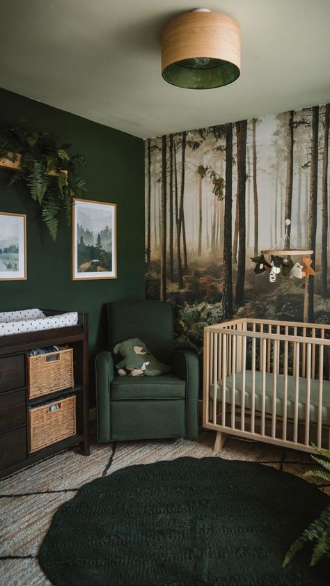 A forest-themed nursery with a woodland mural, dark green walls, a natural wood crib, matching green armchair, wicker storage baskets, and a soft green round rug, creating a cozy and natural ambiance. Nursery Ideas Mural, Mountain Forest Nursery, Vintage Forest Nursery, Baby Room Design Green, Green Forest Nursery, Baby Room Themes For Boys, Green Boys Nursery, Zen Nursery Ideas, Forest Green Room